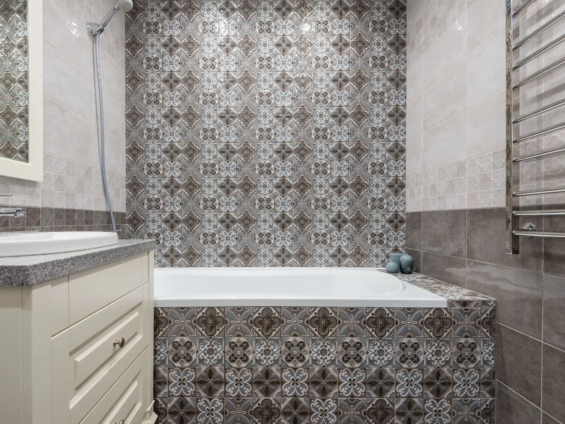 Baño con pared de baldosa estampada, bañera empotrada y lavabo de mueble
