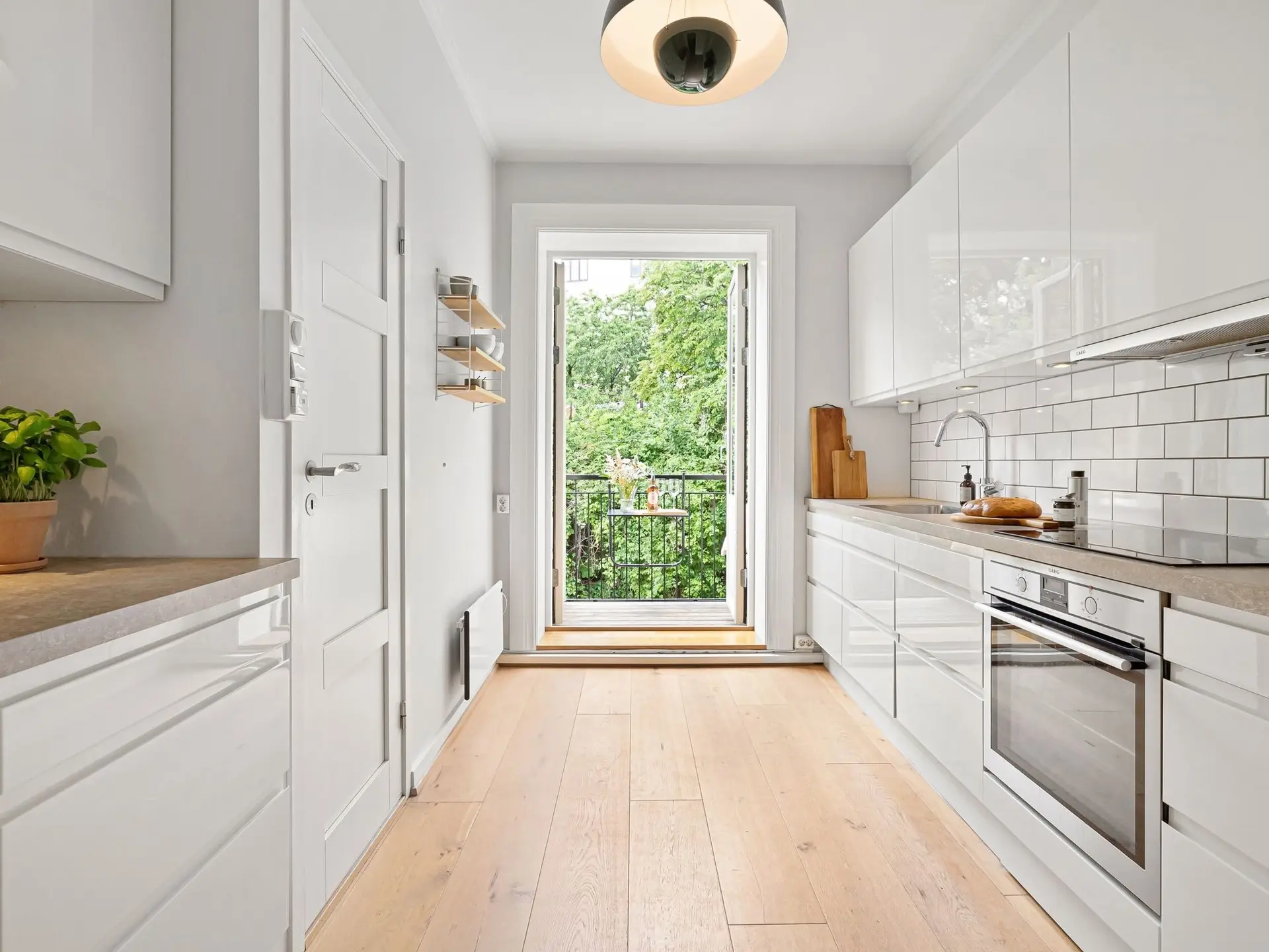 Cocina blanca alargada con encimera de madera y salida a la galería