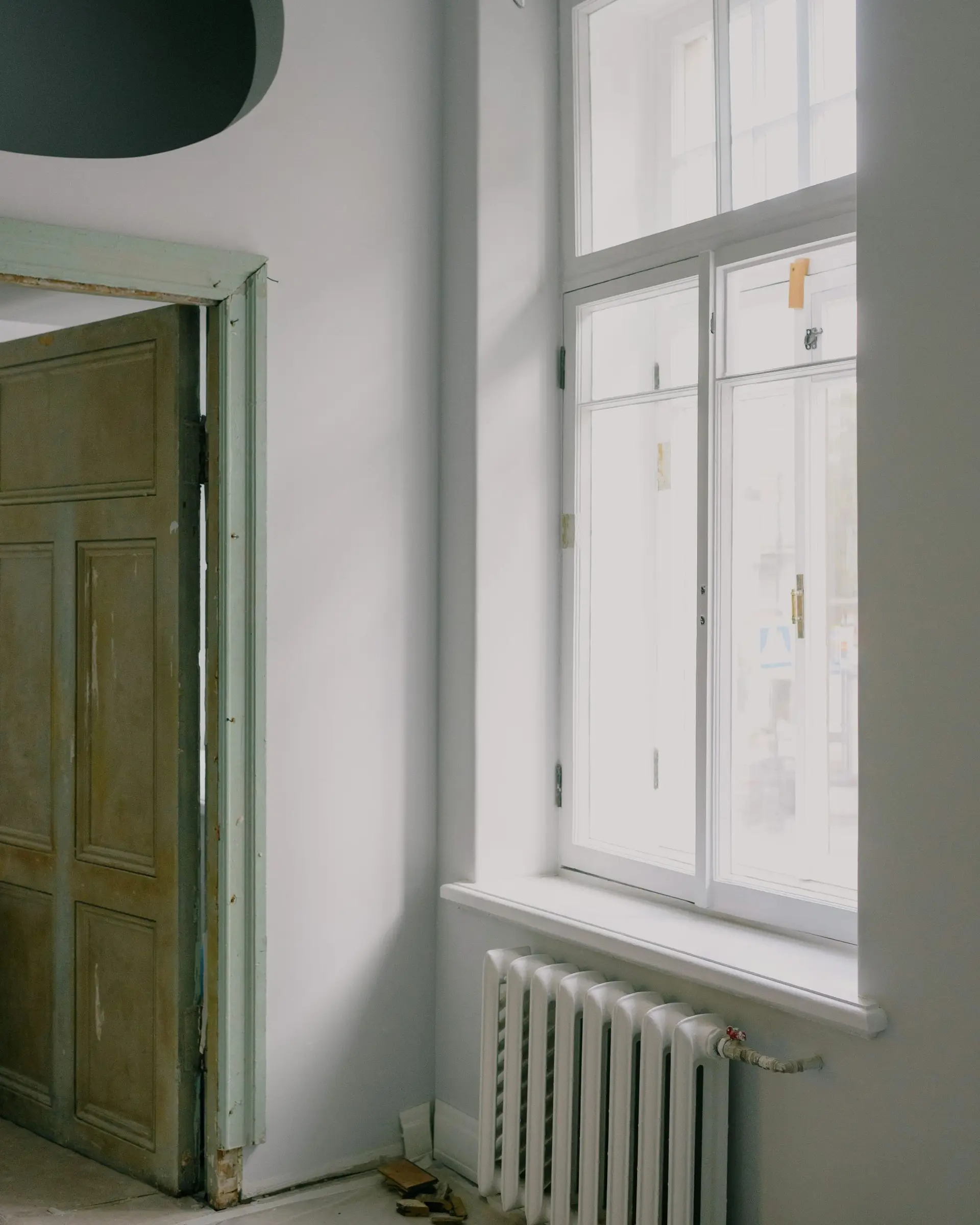 Habitación en obra con hornacina ovalada, puerta de madera antigua y ventana alta